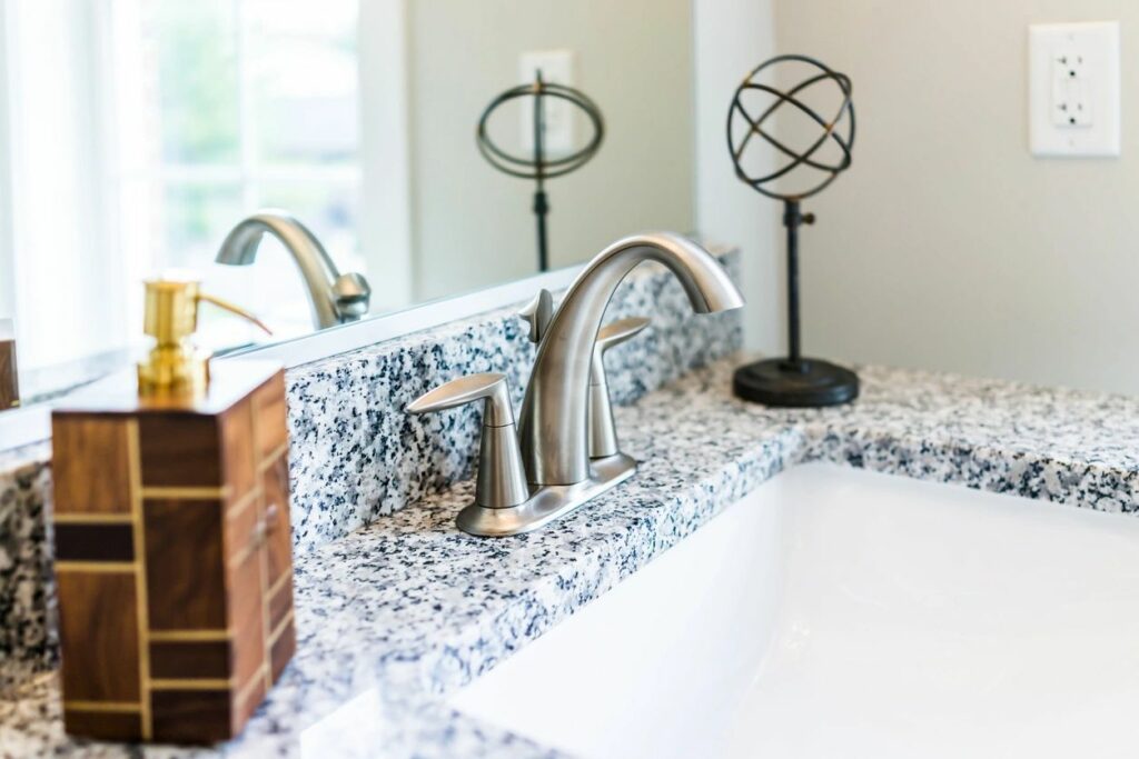 A bathroom sink with marble counter top and silver faucet.